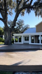 The Alice’s deck shaded by a moss-draped oak tree beside the venue's white and wood-paneled buildings.
