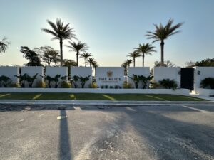 The Alice event venue entrance with white walls, modern landscaping, and tall palm trees in Destin, Florida