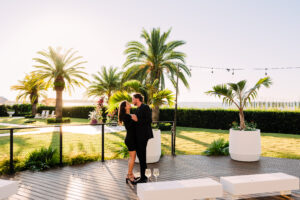 A couple dancing on the tree deck at The Alice at sunset, surrounded by palm trees and waterfront views.
